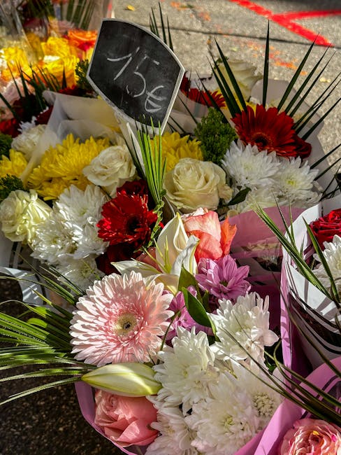 A vibrant assortment of fresh floral bouquets arranged outdoors, featuring a variety of flowers including large pink gerbera daisies, white roses, white chrysanthemums, red gerbera daisies, and pink l